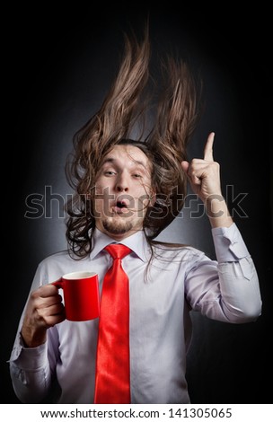 Funny man with hair up holding red mug and pointing up at black background