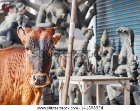 Cow standing nearby statue shop on the street of Mamallapuram in Tamil Nadu, India