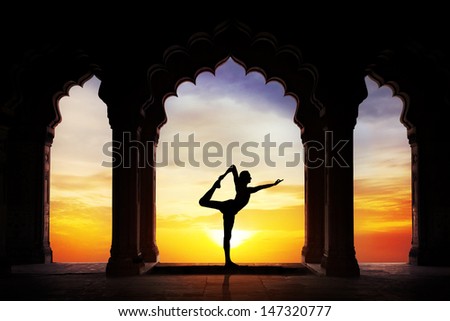 Man Silhouette Doing Yoga In Old Temple At Orange Sunset Sky Background