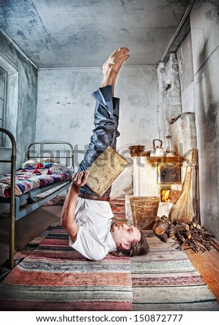 Businessman doing yoga and reading the book in old Russian house with traditional stove