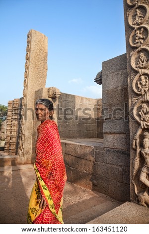 Mamallapuram, INDIA - January 24: Old Indian woman in red sari walking in Mamallapuram Temple on January 24, 2013.