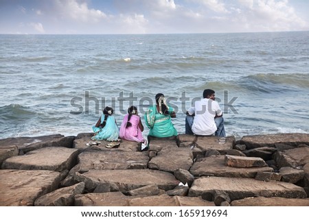 Puducherry, INDIA - January 26: Indian family sitting on the stones near the ocean in Puducherry, also known as Pondicherry, on January 26, 2013.
