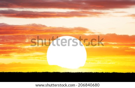Big sun and grass silhouette at dramatic cloudy sky background