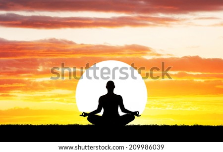 Man silhouette in Yoga meditation pose at big sun background