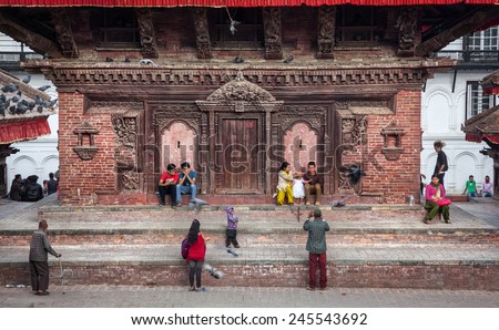 DURBAR SQUARE, KATHMANDU, NEPAL - APRIL 4, 2014: Nepali people sitting at old wooden pagoda near museum of Tribhuvan Nepali King