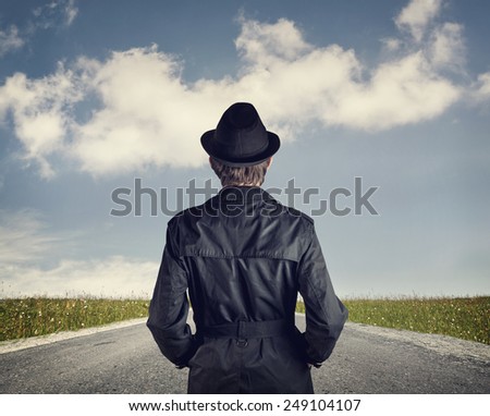 Man in black hat on the road at blue cloudy sky background
