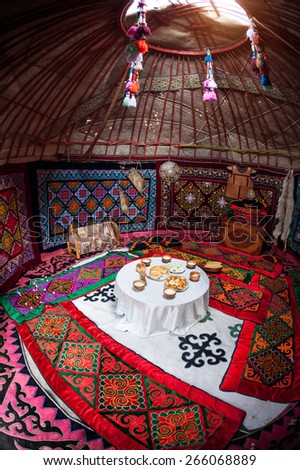 Ethnic nomadic house yurt interior with table of national food at Nauryz celebration