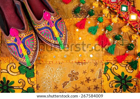 Colorful ethnic shoes and gipsy belt on yellow Rajasthan cushion cover on flea market in India