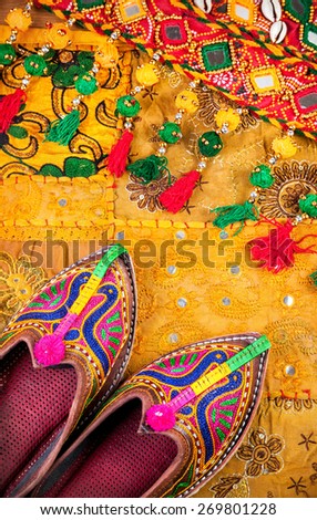 Colorful ethnic shoes and gipsy belt on yellow Rajasthan cushion cover on flea market in India