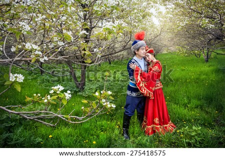Couple in Kazakh costume in Spring Blooming apple garden of Almaty, Kazakhstan, Central Asia