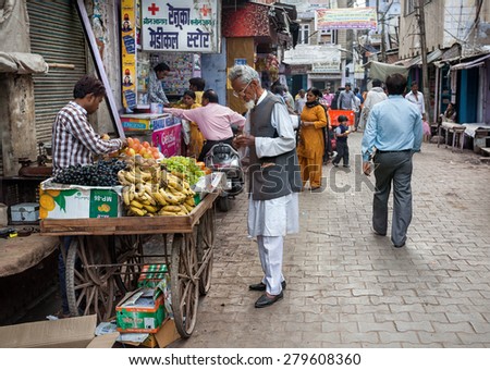 AGRA, UTTAR PRADESH, INDIA - FEBUARY 24, 2015: Muslim man buying fruits from the seller on the Taj Ganj Street