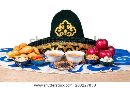 Kazakh national food on the table with national hat and tea at white background