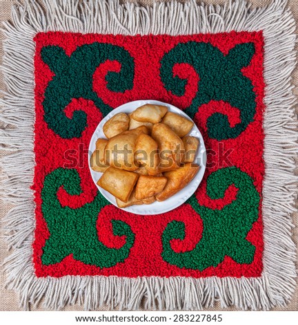 Kazakh national food baursak bread on the ethnic red carpet with oriental green pattern