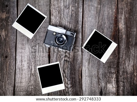Old film camera and polaroid photos with space for pictures on the wooden background