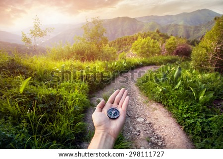 Hand with compass at mountain road at sunset sky in Kazakhstan, central Asia