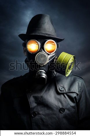 Man in gas mask with explosion in his eyes at dark sky background