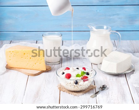 Cottage cheese with cream and berries near other dairy products at blue wooden background