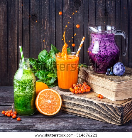 Fresh juice and smoothies with berries, fruits and green spinach on wooden background