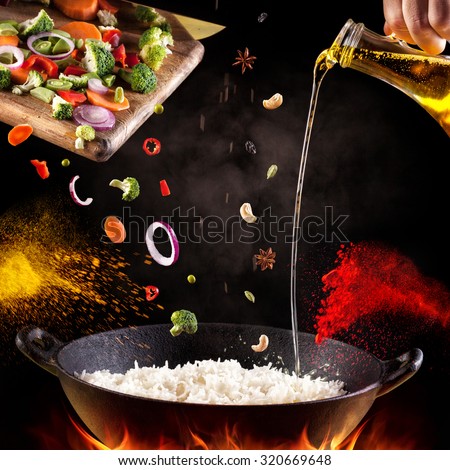 Indian vegetarian biryani with vegetables and spices in cooking process on black background