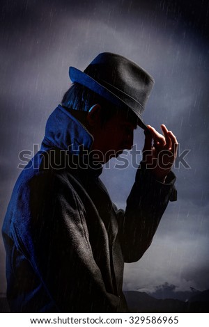 Man in black hat in the rain at dark overcast sky
