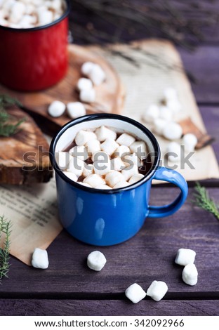 Cocoa with marshmallows in blue and red mugs on wooden table in winter time