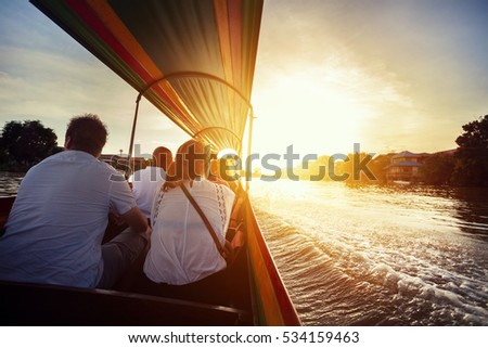 Tourist sitting in long-tail boat cruise by Chao Phraya river in Ancient city Ayutthaya at Sunset, Thailand