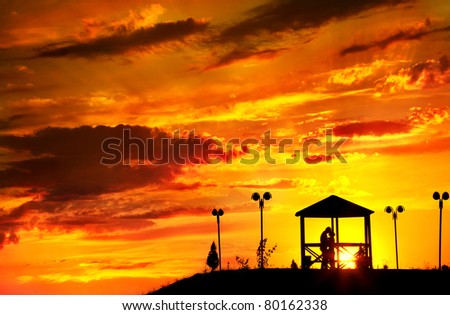 Young couple silhouette hugging and kissing outdoors at sunset background. Sun in summer house