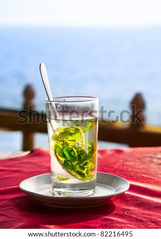 Mint leaves in glass with water on the table in restaurant at ocean background
