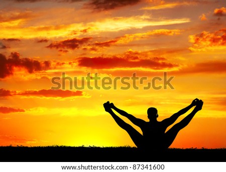 Yoga merudandasana balancing bear pose by Man in silhouette with orange sunset sky background. Free space for text