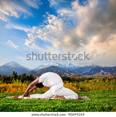 Yoga valakhilyasana backward bending pose by Indian Man in white cloth in the morning at mountain and cloudy sky background