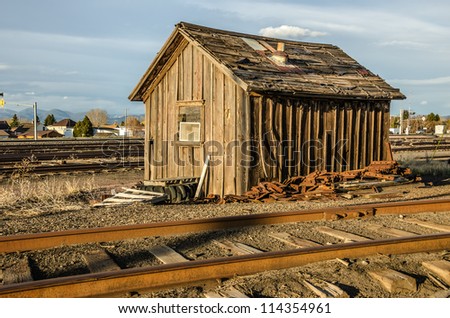 Building in disrepair standing between railroad tracks and piles of debris as the sun begins to set