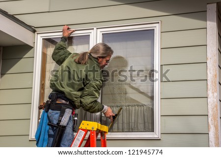 Male window washer using a squeegee to remove a soapy solution from a window to clean the glass