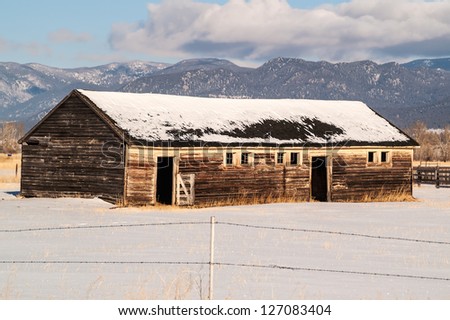 Weathered barn on a ranch in Montana in the winter with a beautiful mountain view