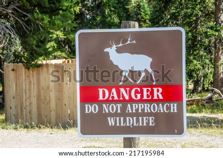 Brown, white, and red sign to warn of the danger of approaching wildlife