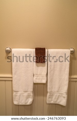Clean towels in a hotel bathroom hanging on a chrome towel rack