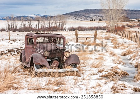 Rusty, dilapidated, abandoned vehicle in a field in rural America on a winter day