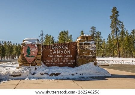 Entrance sign for Bryce Canyon National Park in Utah on a beautiful winter day with a bit of snow..A fir forest is in the background. The sign is made from the limestone that you find in the park.