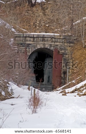 Entrance to abandoned railroad tunnel with wooden doors and fabulous ice formations inside