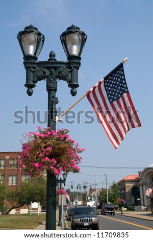 The Stars and Stripes and a pretty hanging basket add color and pride to this lamppost and the downtown area it is in