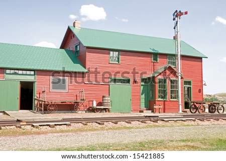 1906 restored train depot with carts, signal light, and railroad tracks at a museum