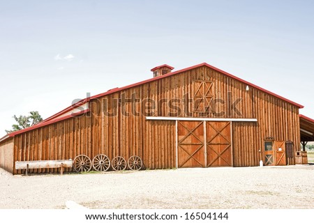 Beautiful barn with wagon wheels, wooden trough, and a milk can in front with loads of room for your message