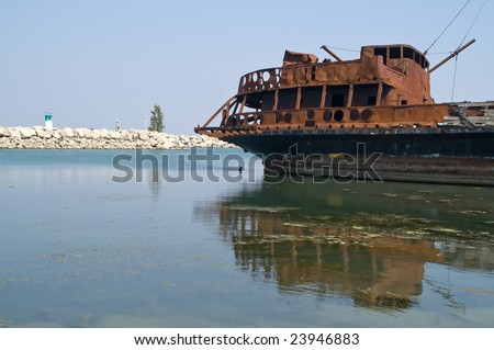 Rusted remains of the burned out cabin of a sailing ship reflected in the water