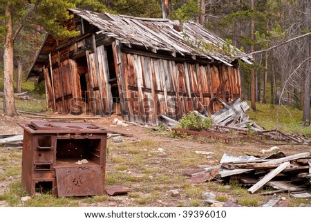 Leaning building with rusty stove and piles of rubble in front in the mining ghost town of Coolidge, Montana