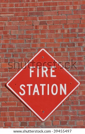 Red and white fire station sign on the outside of a brick fire station