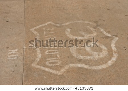 Old Route 66 sign painted on concrete road in Texas hiding under oil drops and smudges