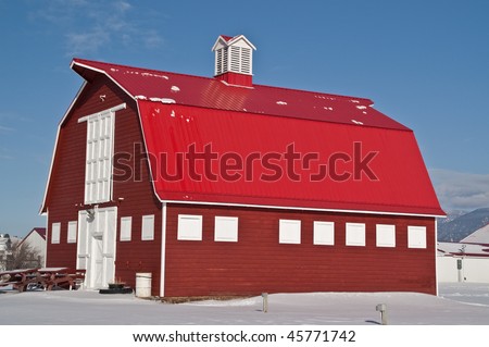 Big red barn with white doors and trim, a red metal roof, and a cupola on the top