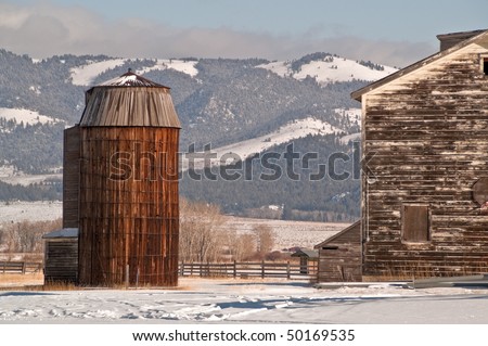 Old farm buildings - silo, farmhouse, other buildings on a beautiful winter day with mountains in the background