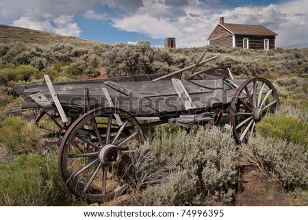 Broken wagon sits downhill from the log school in the ghost town of South Pass City at the South Pass City State Historic Site in Wyoming