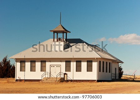 White wood schoolhouse with a school bell in a small tower on top