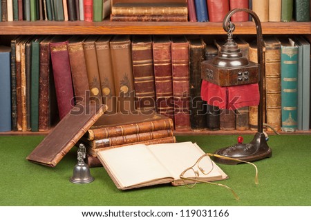 Antique leather books, lamp and reading glasses on green blotter.